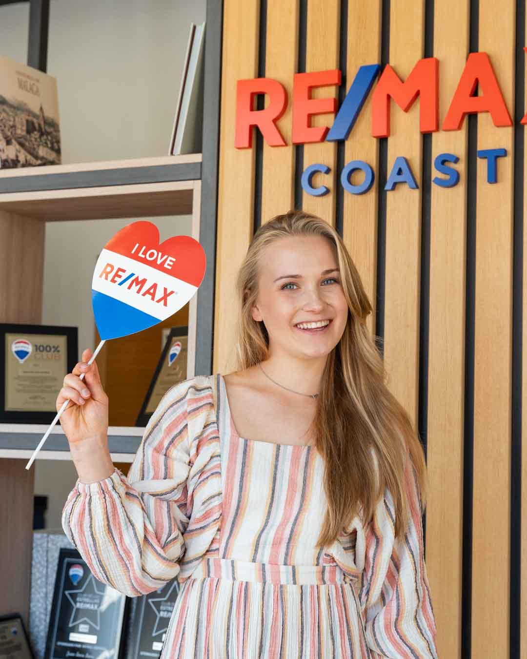 Mujer joven sonriendo en oficina de Remax Coast